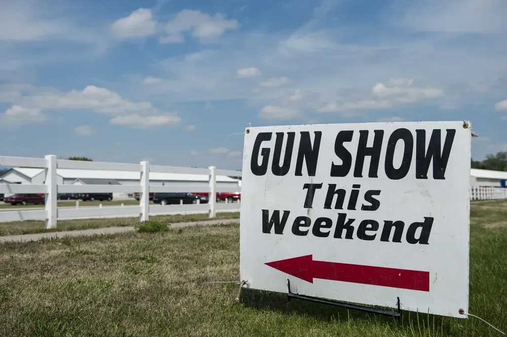 Outdoor sign that says "Gun Show This Weekend" with an arrow