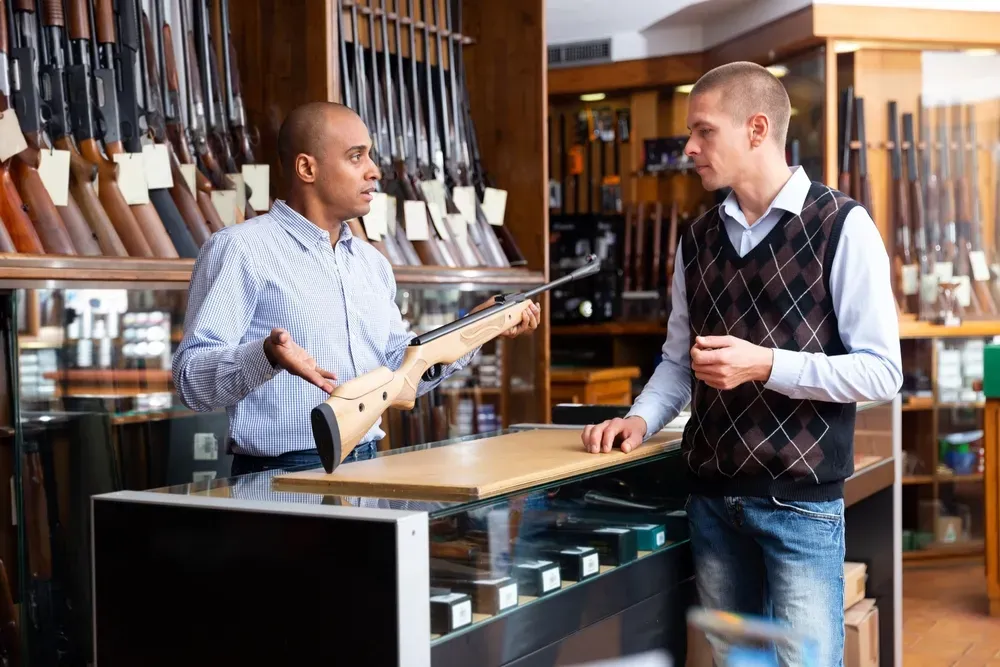 Gun shop employee showing customer a gun