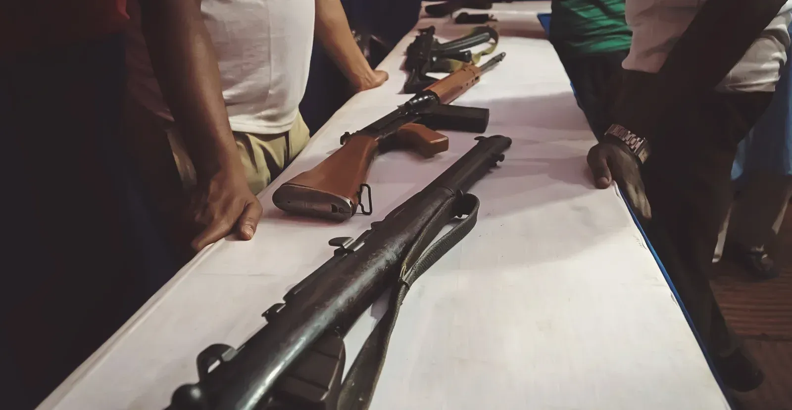 People looking at guns on a table