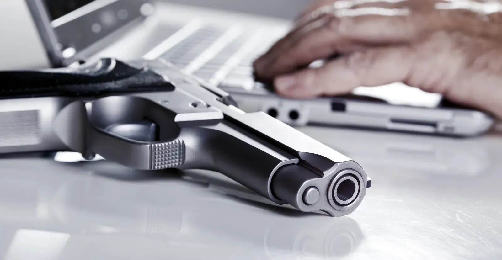 handgun laying next to person using a computer