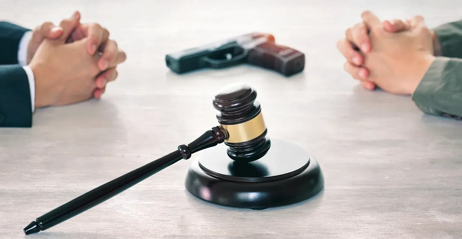 Handgun and a gavel laying between two people