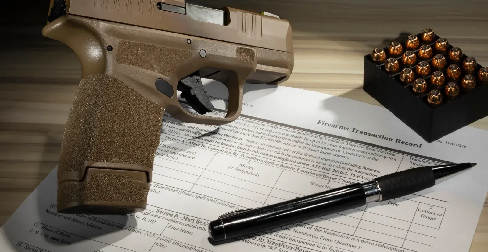 Handgun next to pen and ammo on a firearms transaction record