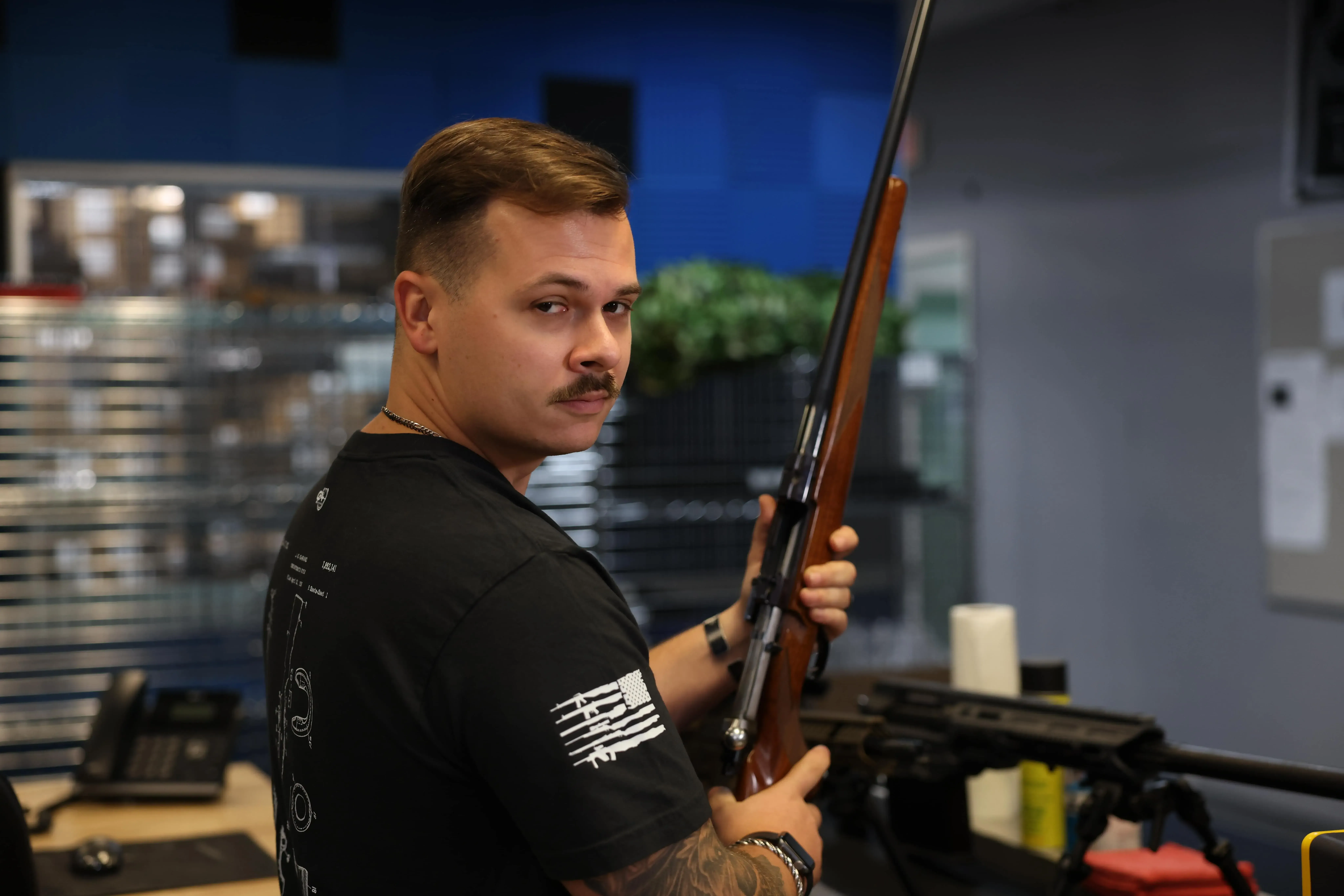 Cash for Arms employee holding a rifle