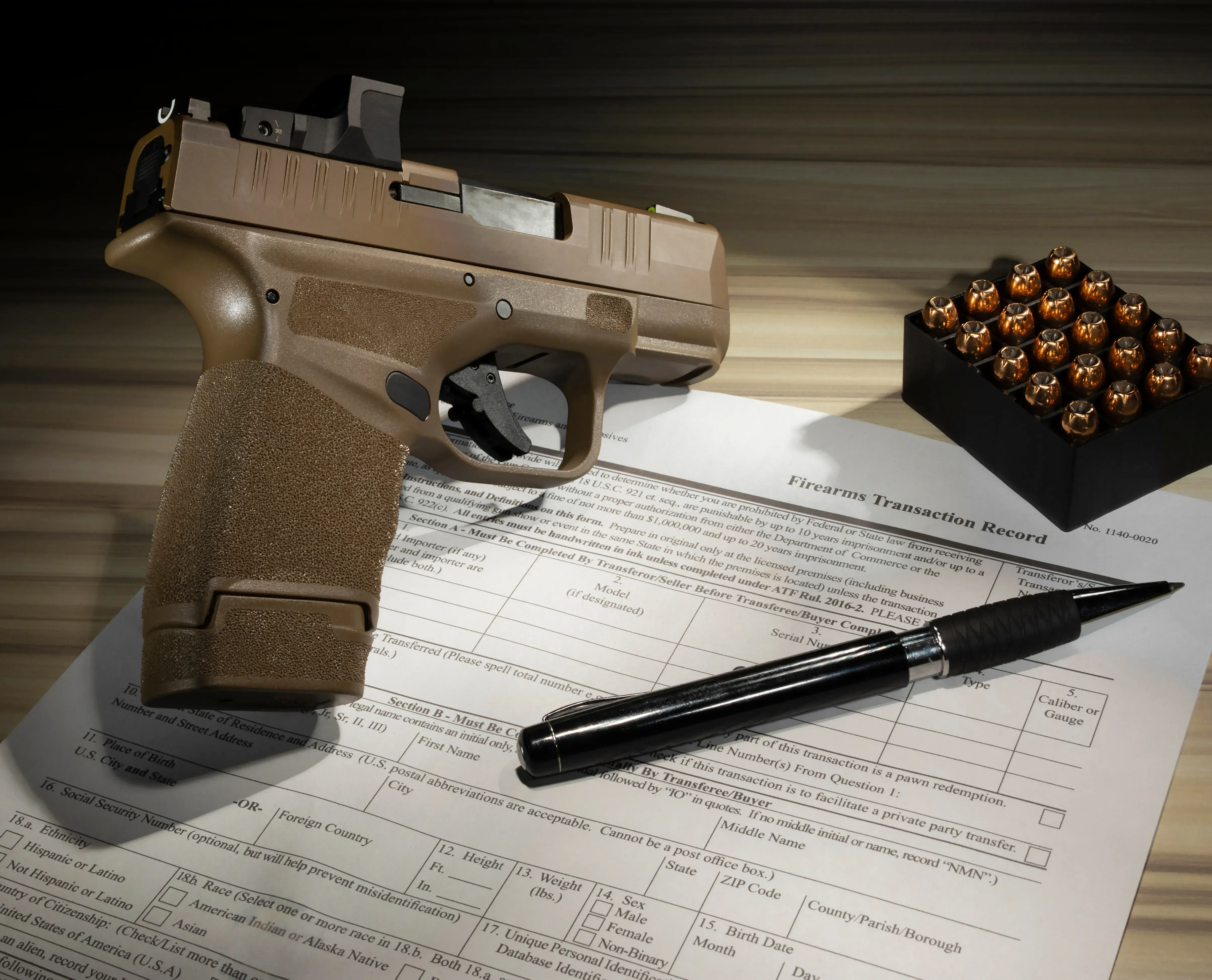 A pistol and a pen on a transaction record with a case of ammuition