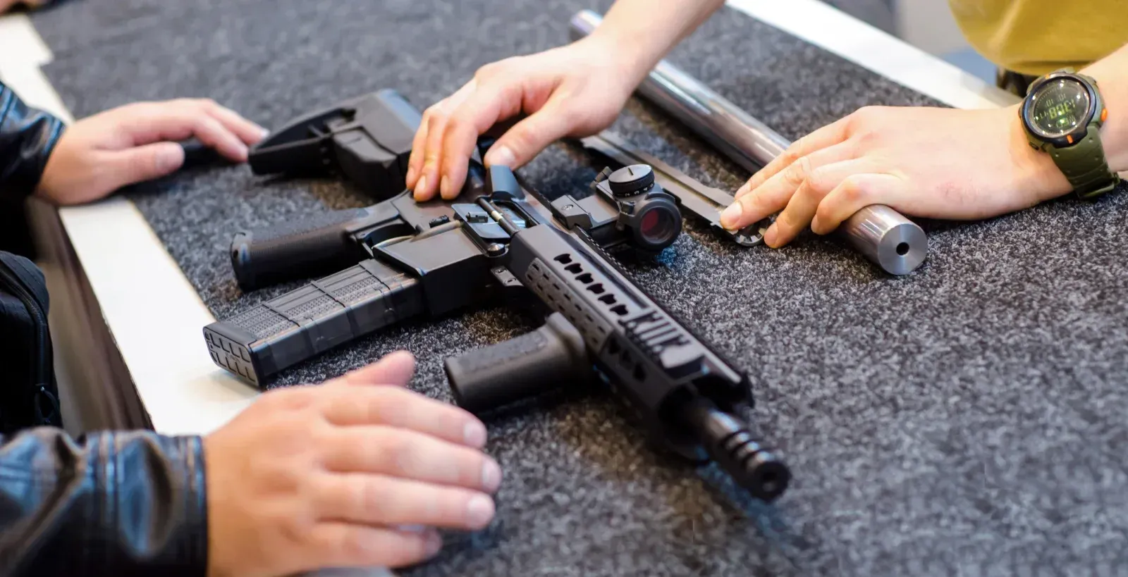 Two people looking at a gun on a counter