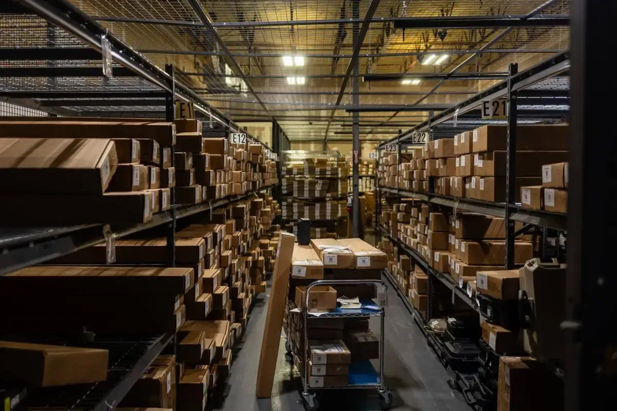 Cash for Arms warehouse aisle showing racked, labeled firearm shipments