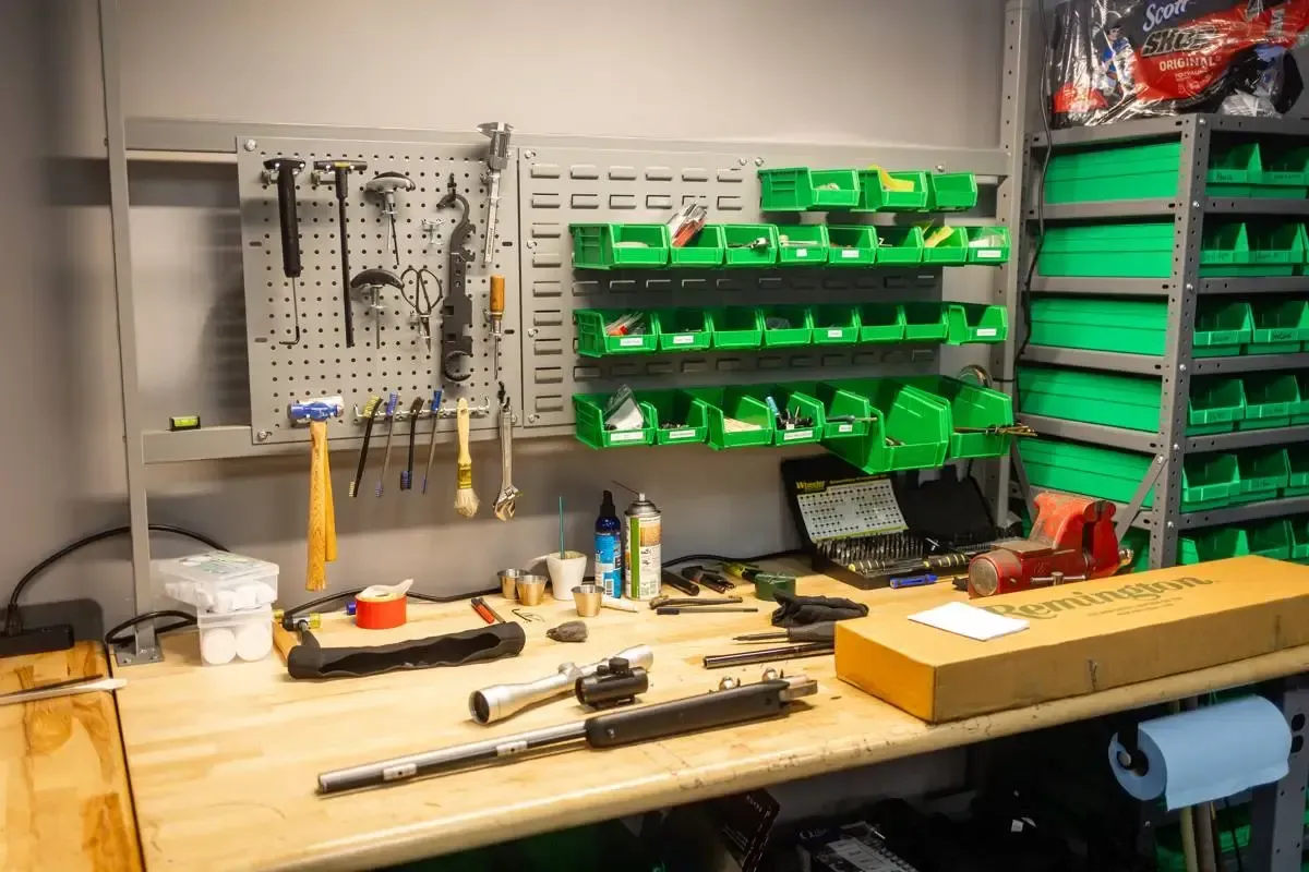 Workbench with firearm tools and a Remington box during intake at Cash for Arms