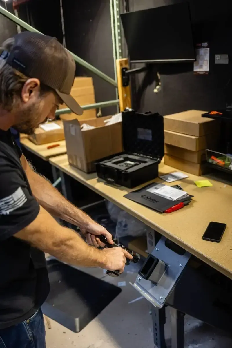 Licensed appraiser inspecting a pistol in a workbench fixture at Cash for Arms